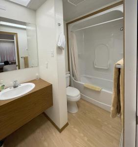 ein Badezimmer mit einem Waschbecken, einem WC und einer Badewanne in der Unterkunft Rest Easy Motel in Three Hills