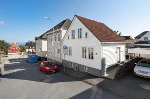 una casa bianca con una macchina rossa parcheggiata in un parcheggio di A Place To Stay Stavanger, apartment 1 a Stavanger