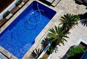 an overhead view of a blue swimming pool with palm trees at Aguia-Vista Paradise Bliss, 3BR, Pool, Beach Walk in Jeffreys Bay