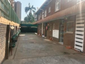 een leeg steegje tussen twee bakstenen gebouwen bij Silent Night Guest House Sunnyside Pretoria in Pretoria