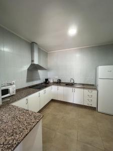 eine Küche mit weißen Schränken und einem weißen Kühlschrank in der Unterkunft Apartamentos Maruja in Los Baños