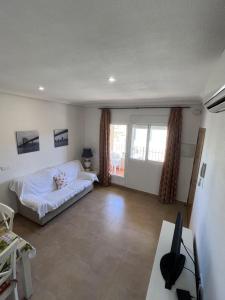 - un salon avec un lit blanc et un bureau dans l'établissement Apartamentos Maruja, à Los Baños
