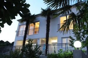 a white house with palm trees in front of it at Apartments Palma in Šibenik