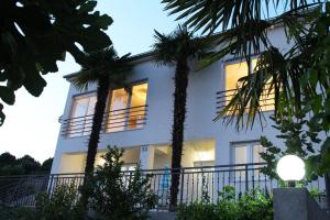 una casa blanca con palmeras delante en Apartments Palma, en Šibenik