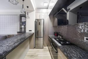 cocina con nevera de acero inoxidable y encimeras de granito en One-BDR Luxury apartment, en Ereván
