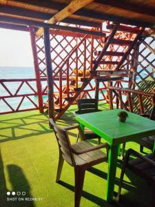 普拉亞布蘭卡的住宿－Posada chikiluky beach，海洋门廊上的绿色桌椅