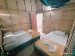 Duas camas num quarto com paredes de madeira em Posada chikiluky beach em Playa Blanca