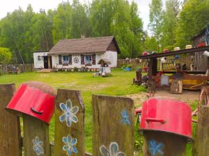 una cerca con flores pintadas en ella delante de una casa en Zagroda Zalipie, en Gostynin