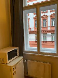 a microwave sitting on top of a refrigerator next to a window at Cosy central apartment in Žižkov in Prague