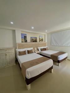 um quarto com 2 camas e um ecrã de projecção em Hotel La Magdalena em Cartagena das Índias