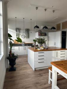 a kitchen with white cabinets and a wooden floor at Old Bank Apartment in Motueka