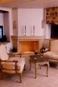 a living room with a fireplace with two chairs and a table at Aegean Diamonds Boutique Villas in Loutraki