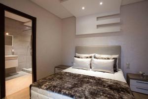 1 Schlafzimmer mit einem großen Bett und einem Badezimmer in der Unterkunft Appartement Cosy Residence avec 2 Piscines in Marrakesch