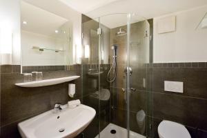 ein Bad mit einem Waschbecken und einer Dusche in der Unterkunft Hotel Villa Neander in Binz