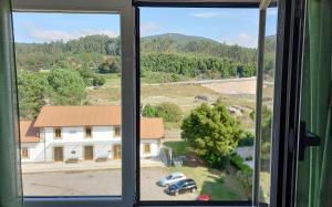 una ventana con vistas a una casa y un coche en Apartamento con vistas al mar en la playa de Vilagarcia - O Feitizo, en Vilagarcía de Arousa