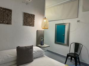 Cette chambre dispose de deux lits, d'une chaise et d'une fenêtre. dans l'établissement El Barrio Hostal, à Carthagène des Indes