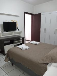 a bedroom with a bed and a flat screen tv at Apartamento 1 in Florianópolis
