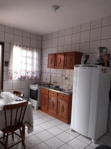 a small kitchen with a white refrigerator and a table at Apartamento 1 in Florianópolis