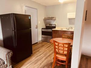 a kitchen with a black refrigerator and a table at Palace Inn & Suites - Newport News/Jefferson Ave in Newport News