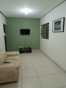 een woonkamer met een bank en een flatscreen-tv bij Pousada cantinho da felicidade in Uberlândia