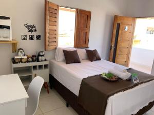 a bedroom with a bed with a table and a window at Suite casal na praia do Preá in Cruz