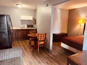 Palace Inn & Suites - Newport News/Jefferson Ave في نيوبورت نيوز: غرفة صغيرة بسرير ومطبخ مع طاولة