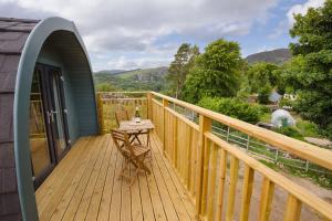 eine Holzterrasse mit einem Tisch auf dem Balkon in der Unterkunft Spectacular Mountain View Ecopod in Newtonmore