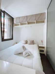 a white bed in a white room with a window at Alojamiento Vilardell in Barcelona