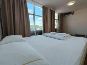 2 witte bedden in een kamer met een groot raam bij Pension Saphir in Bistriţa