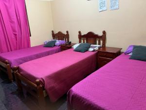 duas camas num quarto com lençóis cor-de-rosa em Hotel y Departamentos Arroyos em Perico