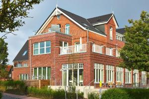 un edificio de ladrillo rojo con techo negro en Lüttjeod Apartmentvilla 01, en Langeoog