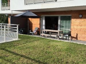 a patio with a table and chairs and an umbrella at Les rives de la jamagne in Gérardmer