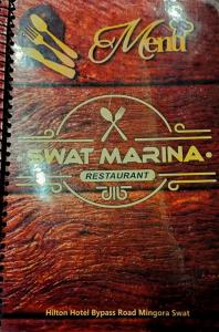 a notebook with the words wet marina on a wooden table at Swat Hilton Hotel by Khan Familia in Swat