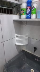 a bathroom with a toilet and a shelf with bottles at Kitnet em Aracaju para 3 pessoas in Aracaju