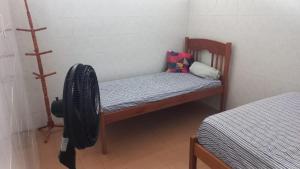 a small room with a bed and a chair with a fan at Kitnet em Aracaju para 3 pessoas in Aracaju