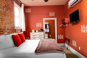 a bedroom with orange walls and a bed with red pillows at Grand Highland Hotel in Prescott