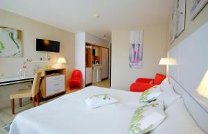コウォブジェクにあるApartment prywatny w Hotelu Diwa w strefie kurortowej z klimatyzacja i Parkingiem wcentrum Kolobrzeguのベッドルーム1室(白いベッド1台、デスク、赤い椅子付)