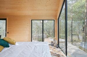 a bedroom with a bed and large glass windows at Forestic Lietuva in Vilionys