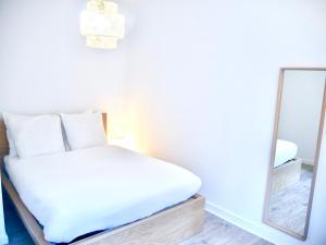 Schlafzimmer mit einem weißen Bett und einem Spiegel in der Unterkunft Travel Rio Logement en Colocation in Sens