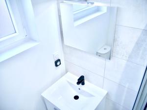 ein weißes Badezimmer mit einem Waschbecken und einem Spiegel in der Unterkunft Travel Rio Logement en Colocation in Sens