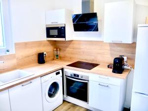 eine Küche mit weißen Schränken, einer Waschmaschine und einem Trockner in der Unterkunft Travel Rio Logement en Colocation in Sens