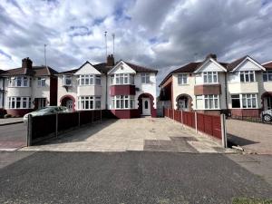 una fila de casas blancas con una valla roja en Large 4 bed Coventry house Contractors Professionals Private parking Close to NEC, en Parkside