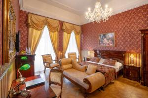 a bedroom with a bed and a couch and a chandelier at Galicia Nueva, castle hotel in Lučenec