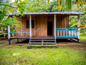 een klein huis met een veranda en een schommel bij Ecohotel Riomar Mecana in Bahía Solano