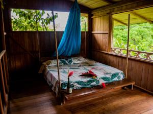 a bed in a room with two windows at Ecohotel Riomar Mecana in Bahía Solano