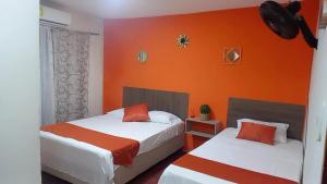two beds in a room with an orange wall at Hostal 4 Manzanas in Santa Marta