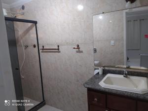 Un baño con lavabo y ducha de cristal. en Suíte praia dos Anjos, en Arraial do Cabo