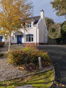 a white house with a tree and a street at Rathmullan Village Home in Rathmullan