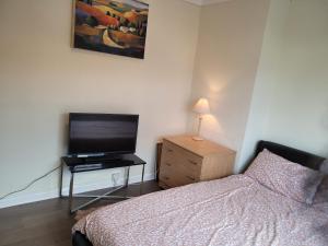 Dormitorio con cama y tocador con TV en Abakwa House en Kingsthorpe