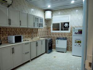 een keuken met witte kasten en een tegelmuur bij Spacious apartments A in Riyad
